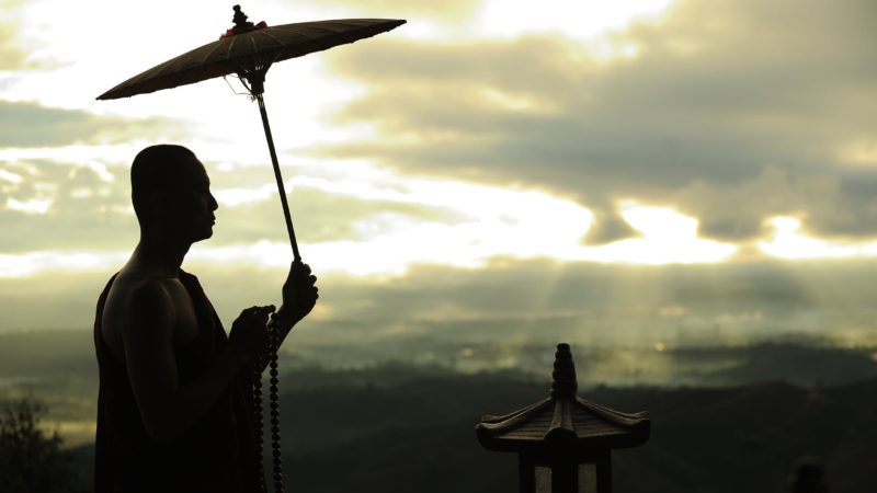 Silhouette Photo of Monk Holding Umbrella